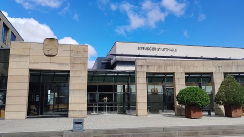Eine moderne Gebäudeansicht der Stralsunder Stadthalle. Vor dem Gebäude sind gepflegte Pflanzen in Töpfen zu sehen.
