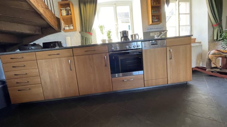 Une cuisine moderne avec des armoires en bois et une table de cuisson. De grandes fenêtres permettent d'avoir beaucoup de lumière naturelle.