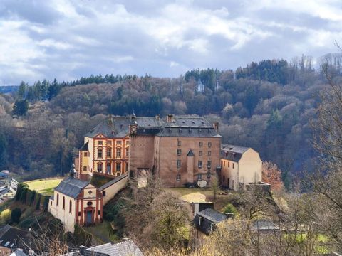 Eine alte Burg auf einem Hügel, umgeben von Bäumen und einer malerischen Landschaft. Der Himmel ist bewölkt und verleiht der Szene eine geheimnisvolle Atmosphäre.