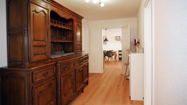 Een gezellige hal met een klassiek ontworpen houten kast. De lange hal verbindt de kamers.