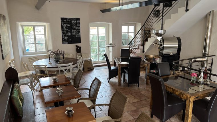 Un café confortable avec des tables et des chaises.
De grandes fenêtres et un escalier ouvert créent une ambiance accueillante.