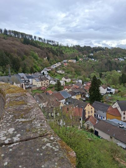 Une ville pittoresque entourée de collines et de forêts verdoyantes. Les maisons sont colorées et disposées le long d'une douce courbe.