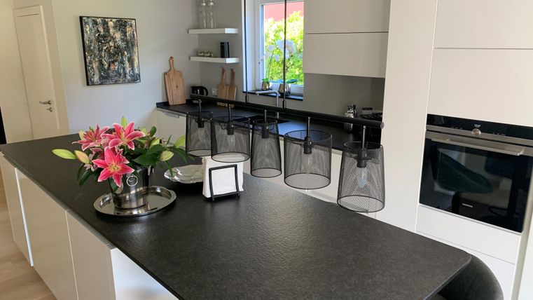 Moderne keuken met een elegante keukenkraan en stijlvolle lampen. Verse bloemen geven de ruimte een uitnodigende sfeer.