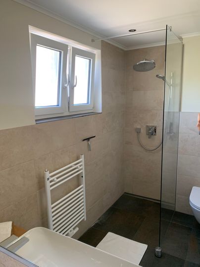 Een moderne badkamer met een douche en een vrijstaand bad. Grote ramen zorgen voor veel daglicht.