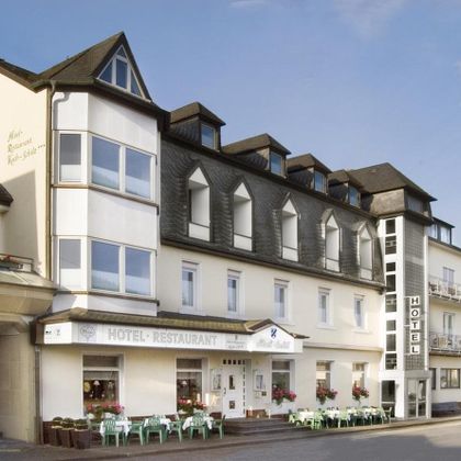 Ein charmantes Hotel mit Restaurant, das eine einladende Fassade und große Fenster hat. Es gibt Sitzmöglichkeiten im Freien und eine ruhige Umgebung.