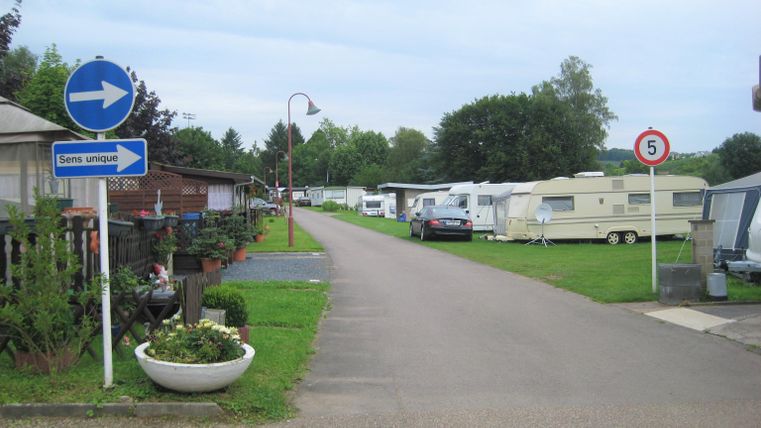 Een camping met caravans aan beide kanten van de weg. De omgeving is groen en de weg loopt recht vooruit.