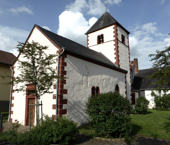 Small church with red brick pattern and tower, surrounded by trees and bushes under a blue sky., &copy; Elke Wagner, Felsenland S&uuml;deifel Tourismus GmbH