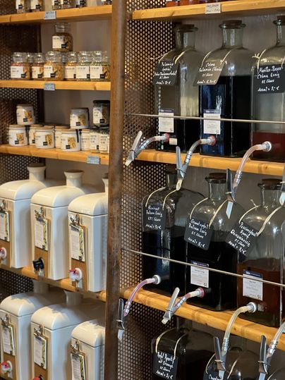 Un magasin bien agencé avec différents conteneurs. Des bocaux et des distributeurs avec différentes liquides et petits produits sont posés sur des étagères.