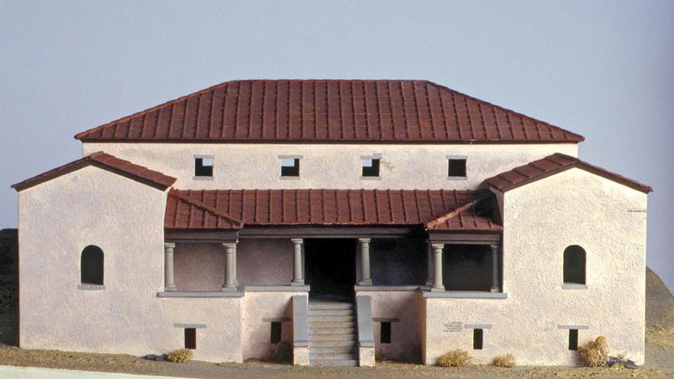 Ein Modell eines historischen Gebäudes mit einem roten Ziegeldach. Die Fassade ist in sanften Farben gehalten und hat mehrere Fenster und Eingänge.