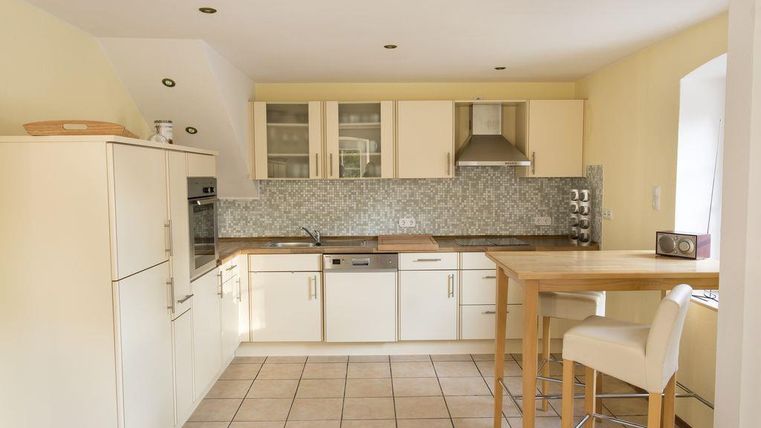 A modern kitchen with white furniture and a bright, friendly atmosphere. The kitchen features a cooking island and a functional layout.