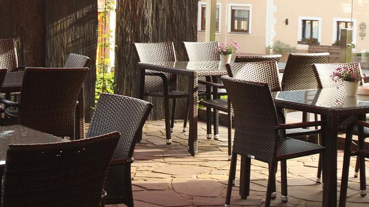 Un restaurant élégant avec des tables et des chaises en extérieur. L'environnement semble calme et accueillant.