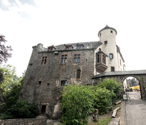 Burg Neuerburg mit steinernen Mauern und einem Turm. Ein Torbogen f&uuml;hrt zu einem Innenhof. Umgeben von B&auml;umen und Pflanzen., &copy; Eifel Tourismus GmbH, D. Ketz