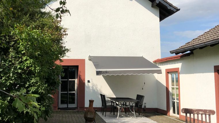 A beautifully designed house with a garden and a terrace. The outdoor area is well-maintained and offers seating.