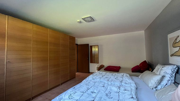 Ein modernes Schlafzimmer mit einem großen Bett und einer Holzkommode. An der Wand hängt ein minimalistisches Kunstwerk.