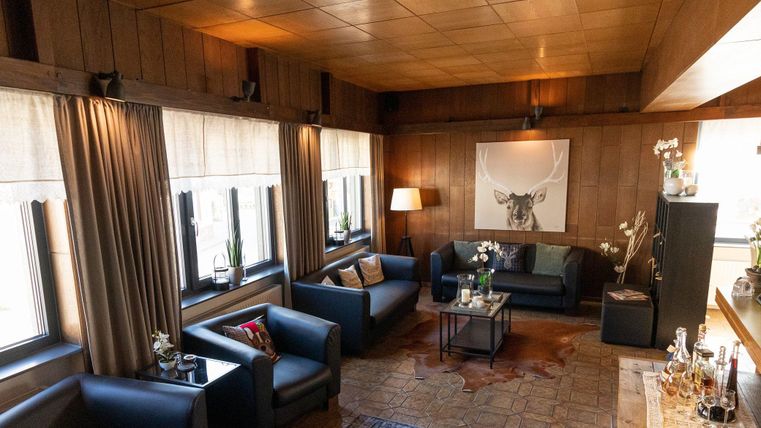 Ein stilvolles Wohnzimmer mit modernen Möbeln und großen Fenstern. Die gemütliche Atmosphäre wird durch Pflanzen und dekorative Elemente ergänzt.