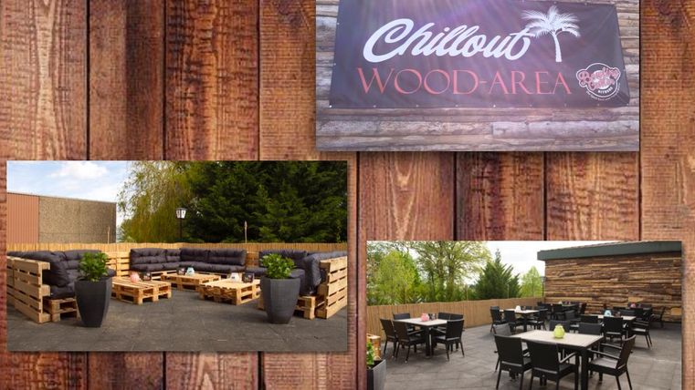 Un espace extérieur rustique avec des sièges confortables en palettes en bois. L'espace est idéal pour se détendre et est entouré de plantes vertes.