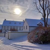 Een winterhuis bedekt met sneeuw onder een heldere lucht. De zon schijnt en geeft de scène een warme gloed.