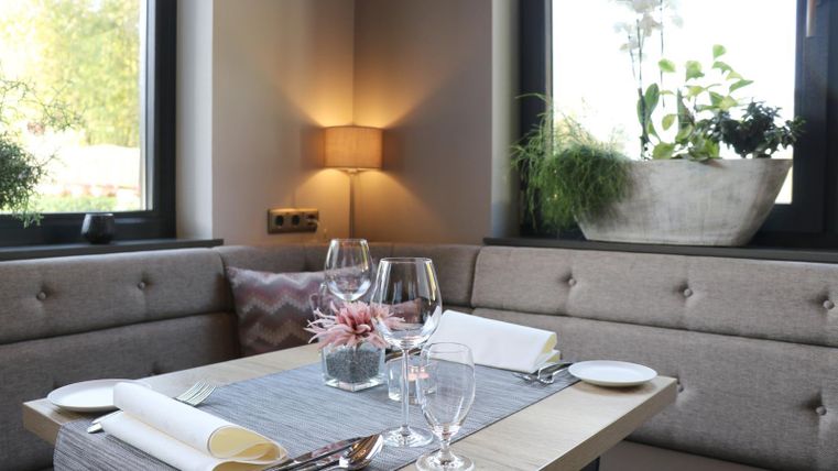 Une table élégante pour deux personnes dans un restaurant. La décoration et les plantes créent une atmosphère conviviale.