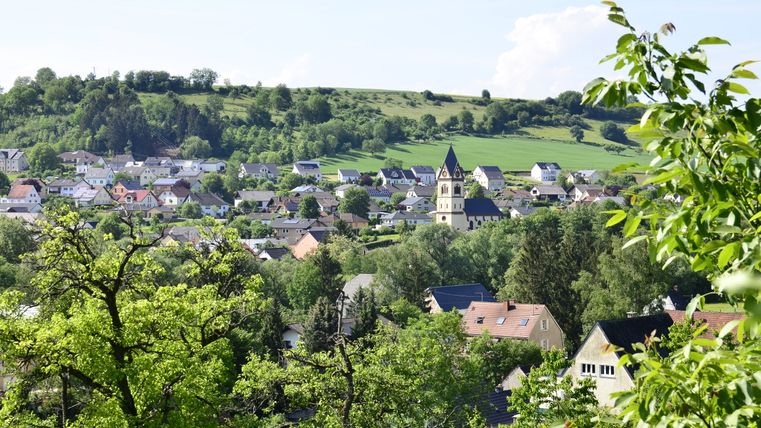 Panoramic view of the village of Oberweis with church and green landscape in the background.