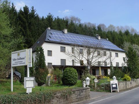 Une maison moderne avec des panneaux solaires sur le toit. Entourée d'arbres et d'un jardin soigné.