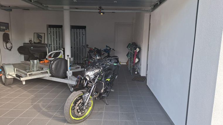 A modern motorcycle depot with a black machine and yellow accents. In the background, more vehicles and bicycles are visible.