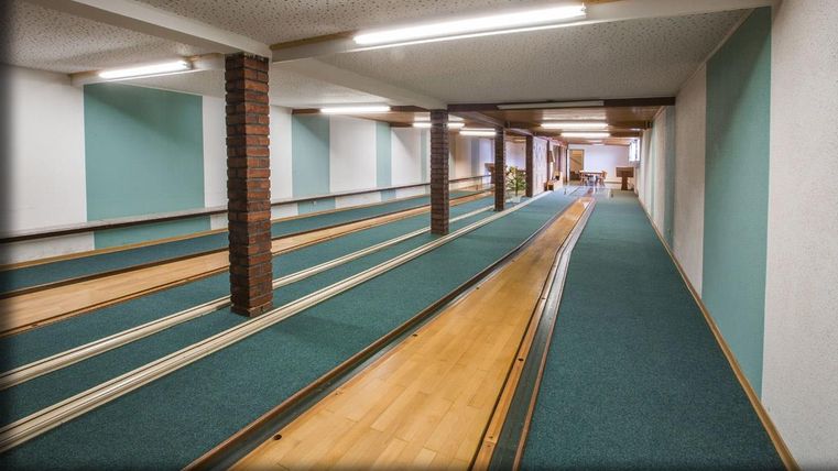 Une salle de bowling avec plusieurs pistes de bowling et un intérieur lumineux. Les murs sont peints dans des couleurs douces et l'éclairage est agréable.