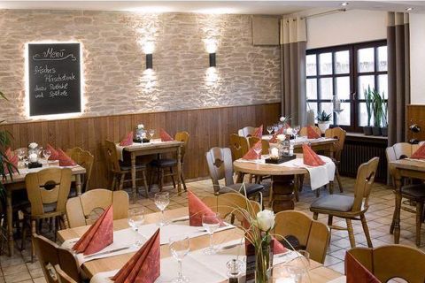 Un restaurant accueillant avec une ambiance rustique.
Les tables sont soigneusement dressées, et il y a un tableau avec le menu.