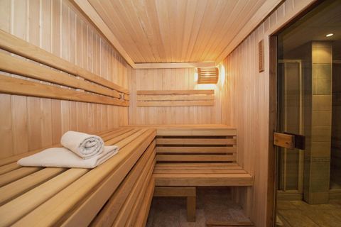 Eine helle Sauna mit Holzbänken und sanfter Beleuchtung. Ein frisches Handtuch liegt bereit.