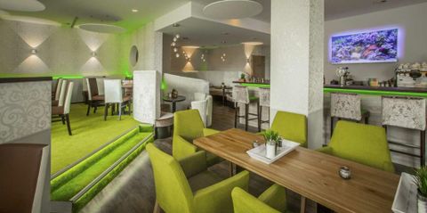Un restaurant moderne avec des chaises vertes et une ambiance élégante. L'intérieur est lumineux et accueillant, idéal pour un repas détendu.