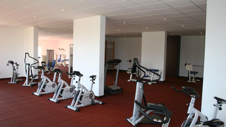 Een modern fitnesscentrum met meerdere trainingsapparaten. De ruimte is helder en goed uitgerust.