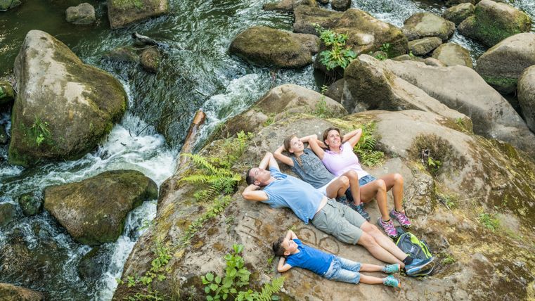 Familie liegt auf Felsen bei Wasserfall