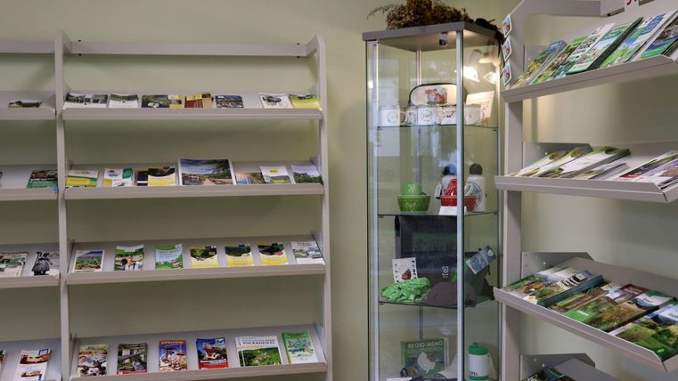 Une pièce avec des étagères présentant divers matériels d'information et brochures. En arrière-plan, il y a une vitrine en verre avec d'autres produits.