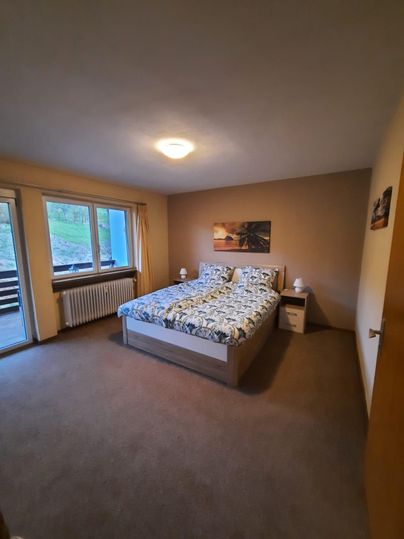 Ein gemütliches Schlafzimmer mit einem großen Bett und einem hellen Fenster. Die Wände sind in neutralen Farben gehalten und es gibt ein Bild an der Wand.