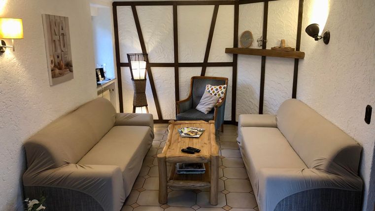 A cozy living space with two sofas and a wooden table. On the wall, there are some decorative elements and lamps.