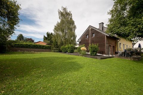 Une maison moderne au milieu d'un jardin verdoyant. Entourée d'arbres et d'arbustes, elle offre un refuge paisible.