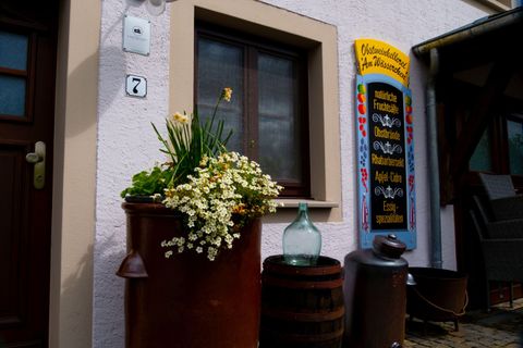 A cozy house with a window and a colorful table. In front of the window stands a pot with flowers and a glass container.