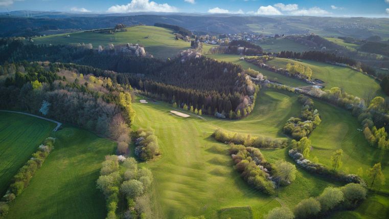 Un paysage pittoresque avec des collines douces et de l'herbe verte. Le ciel est partiellement nuageux et la beauté naturelle des environs est impressionnante.