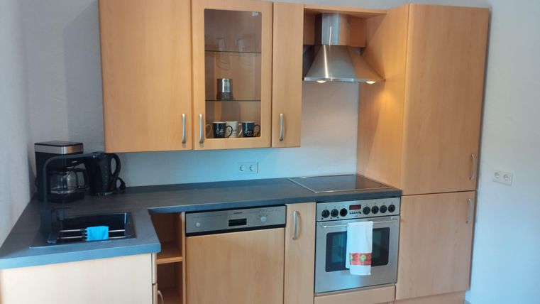 Een moderne keuken met lichte houten kasten en roestvrijstalen apparaten. De ruimte is goed verlicht en biedt een praktische indeling van de keukenbenodigdheden.