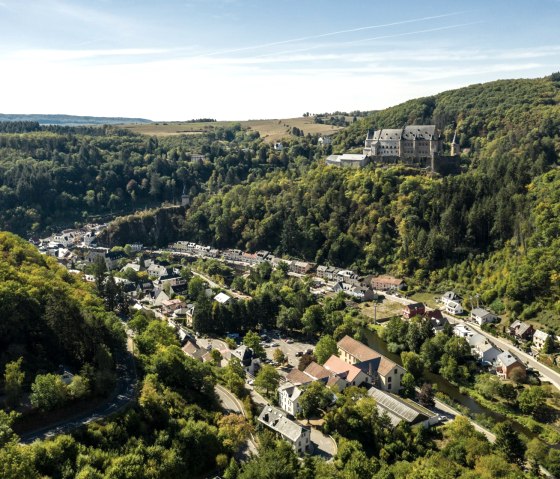 Luftaufnahme von Vianden, Luxemburg, mit dem Schloss auf einem bewaldeten Hügel und der Stadt im Tal., © Eifel Tourismus GmbH, D. Ketz
