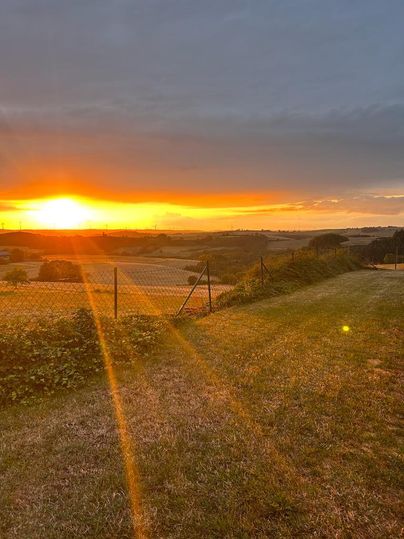 Een adembenemende zonsondergang boven open velden. De kleuren aan de lucht stralen in warme geel- en oranjetinten.
