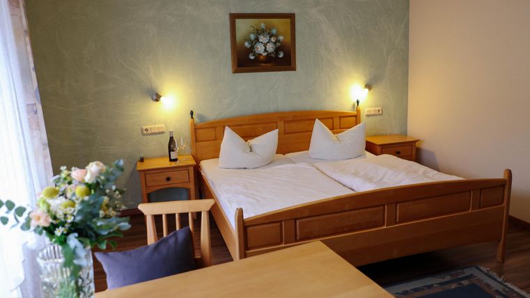 Une chambre confortable avec un lit double et des meubles en bois. Un vase de fleurs et une table complètent l'atmosphère agréable.