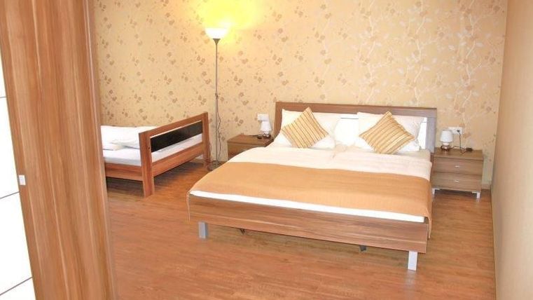 Ein gemütliches Schlafzimmer mit einem großen Doppelbett und einem Einzelbett. Die Wände sind hell und mit floralen Mustern dekoriert.