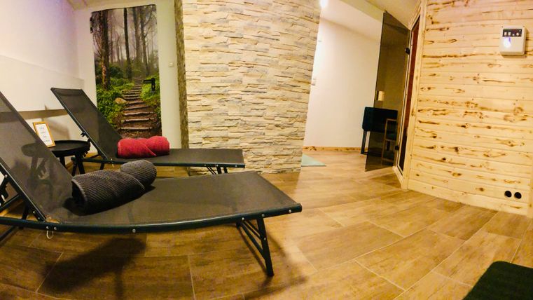 A tranquil relaxation area with two loungers and a stone wall. In the background, there is a picture of a forest path.