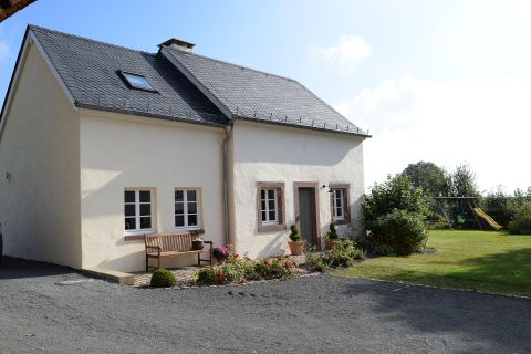 Ein charmantes Haus mit einem Garten und einer Bank. Die Umgebung ist grün und lädt zum Entspannen ein.