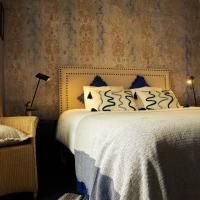 Een gezellig slaapkamer met een groot bed en decoratieve kussens. De muren hebben een stijlvolle structuur, en de verlichting zorgt voor een warme sfeer.