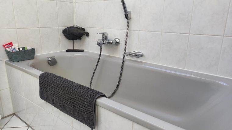 Eine elegante Badewanne in einem hellen Badezimmer. Handtücher und Pflegeprodukte stehen neben der Wanne bereit.