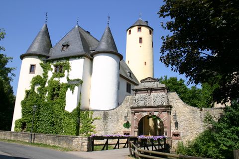 Burg Rittersdorf mit Türmen und Torbogen, umgeben von Bäumen.