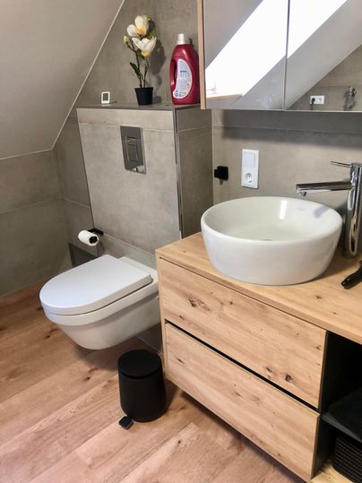A modern bathroom with an elegant sink and a toilet.
Wood and gray elements give the space a contemporary design.