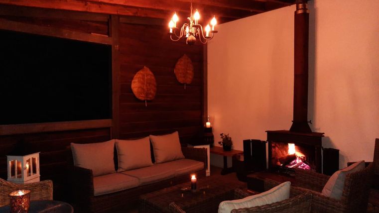 Ein gemütlicher Raum mit einer warmen Atmosphäre. Es gibt bequeme Sitzgelegenheiten und einen Kamin, der für zusätzliche Gemütlichkeit sorgt.