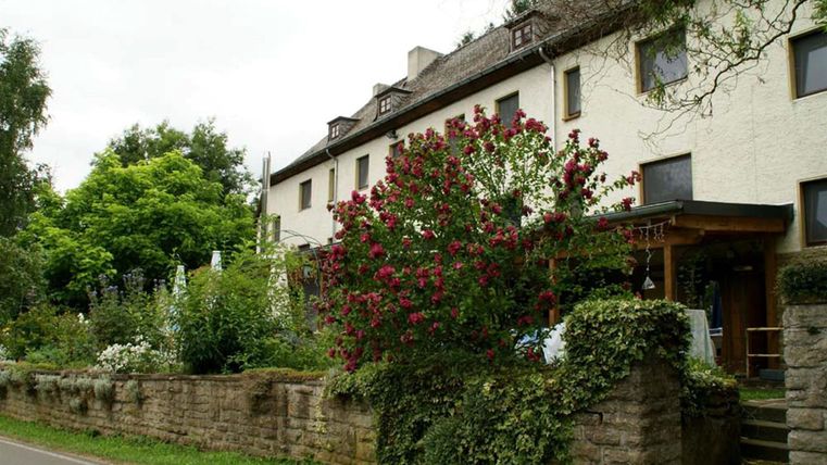 Un bâtiment charmant avec un jardin rempli de fleurs et de plantes vertes. L'environnement est calme et accueillant.